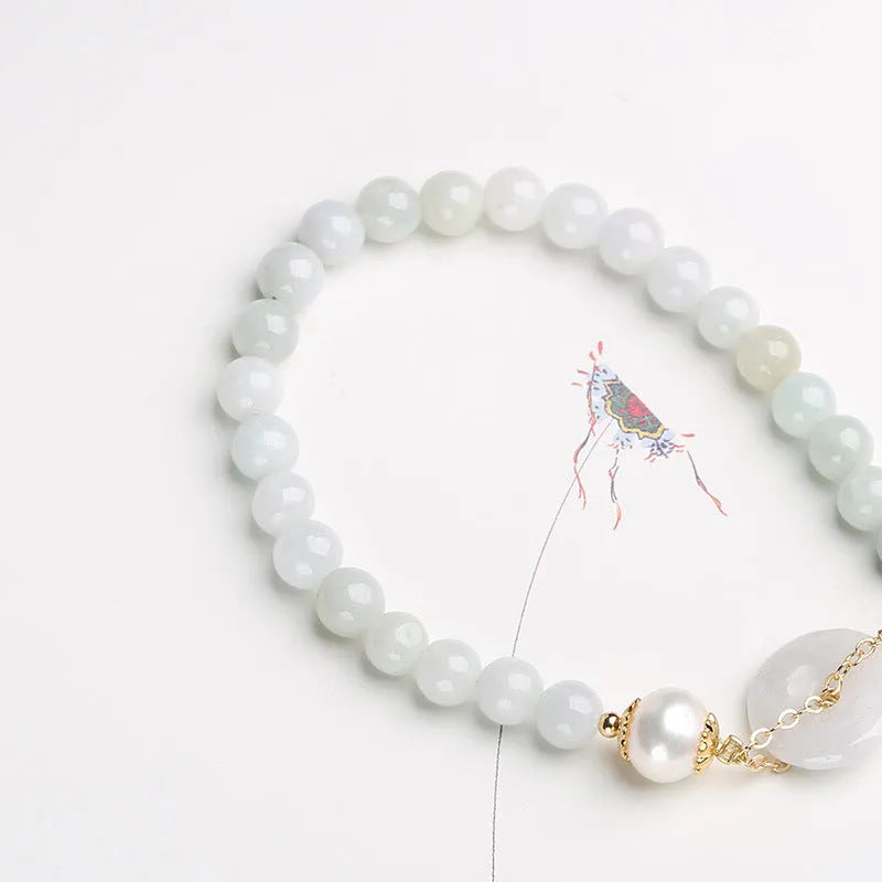 Jade green bracelet with peace buckle fastener and round pearl charms on wrist