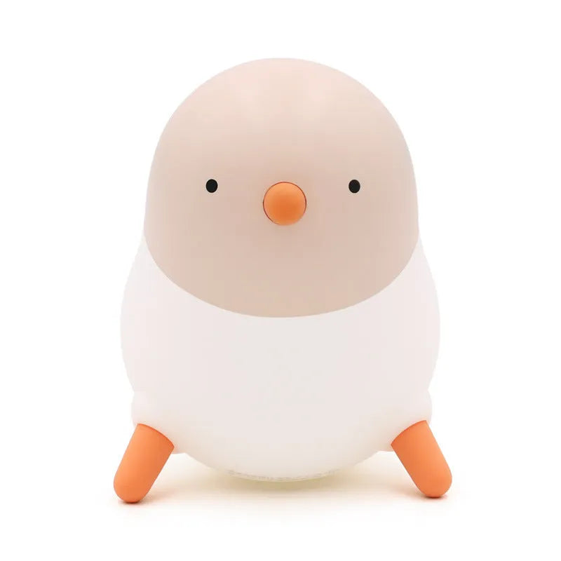 Pecking rice chicken small night light with warm yellow glow on a wooden bedside table, USB charging cable visible