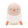 Pecking rice chicken small night light with warm yellow glow on a wooden bedside table, USB charging cable visible