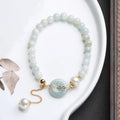 Jade green bracelet with peace buckle fastener and round pearl charms on wrist