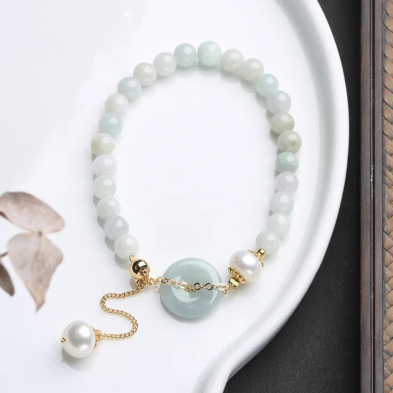 Jade green bracelet with peace buckle fastener and round pearl charms on wrist