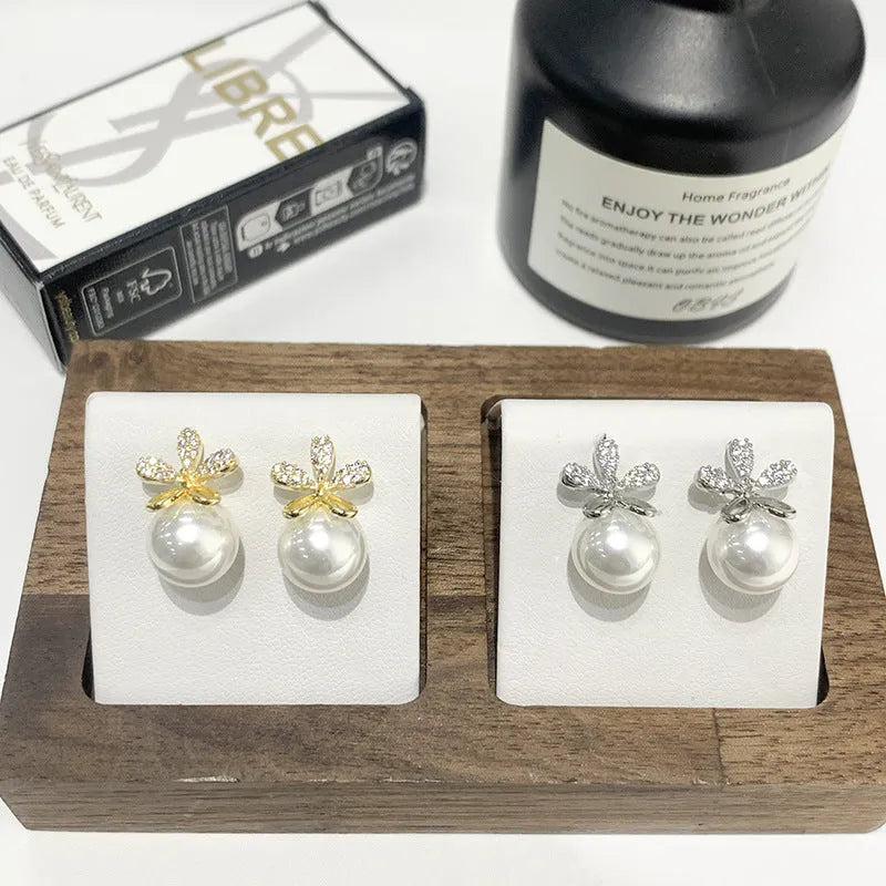 Pair of pearl flower drop earrings in gold and silver finishes on a light background