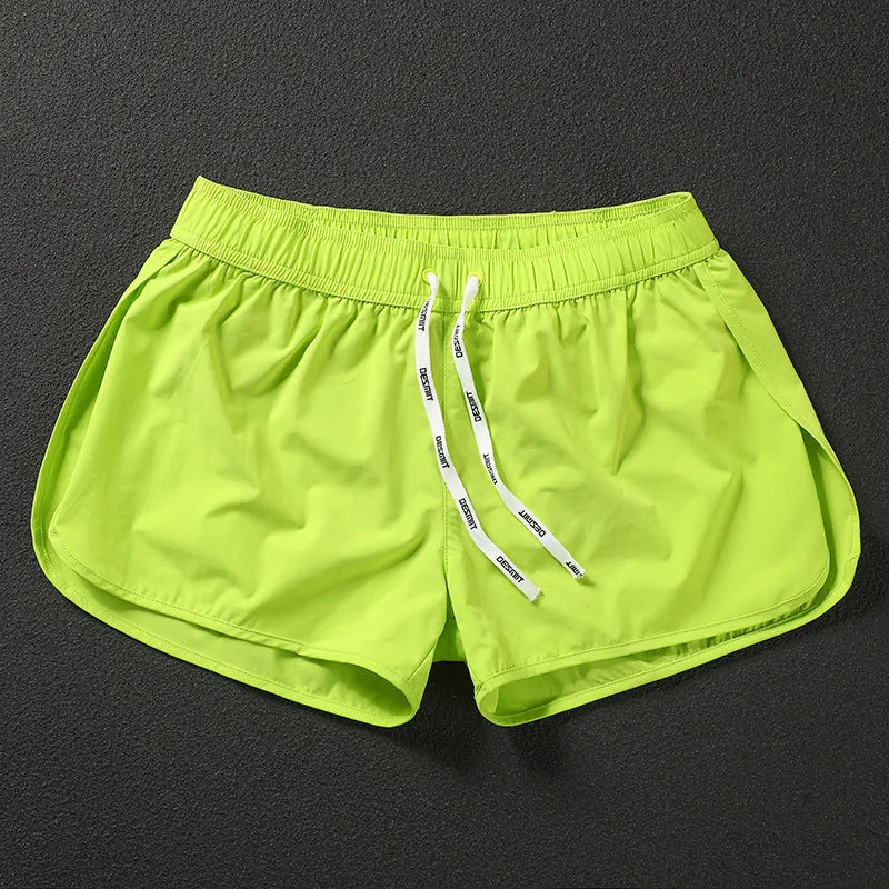 Man wearing loose orange red polyester beach shorts with elasticated waistband.