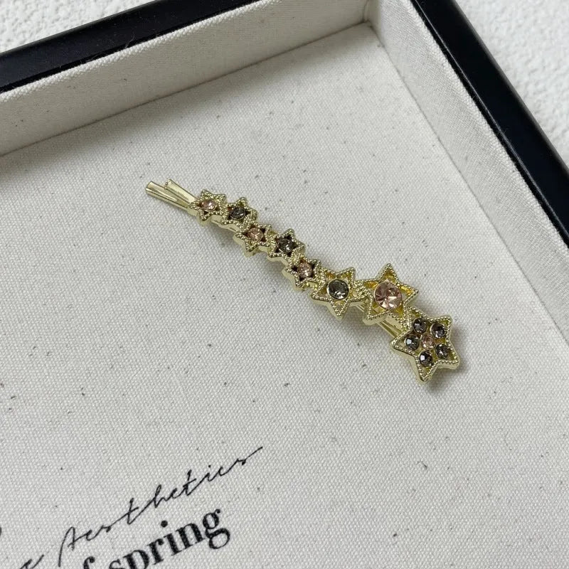 Gold-coloured alloy hair barrette with five-pointed star decoration and side-clip mechanism