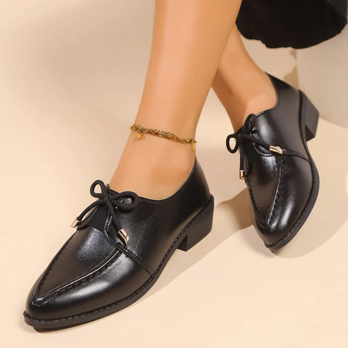 Women's beige loafers with a large decorative bow, showcasing rounded toe and slip-on design.