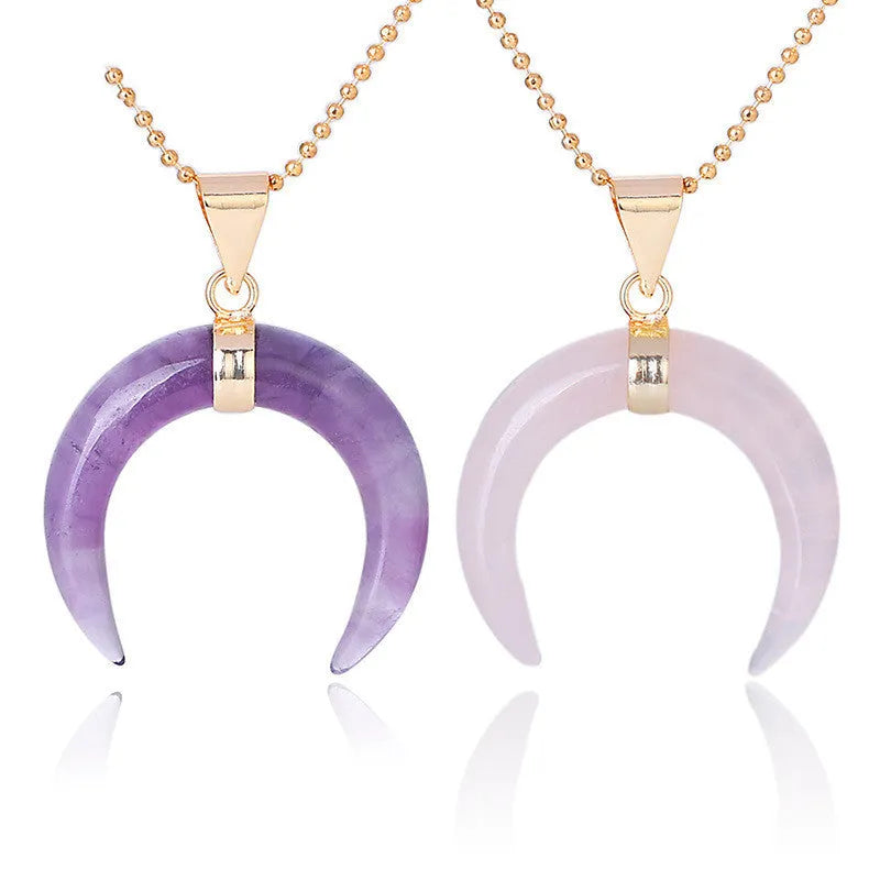 Close-up of a moon pendant necklace with a pink natural stone, on a copper-coloured chain against a neutral background.