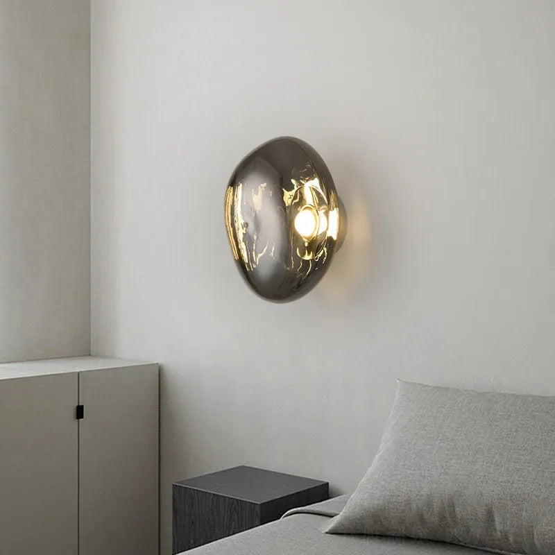 Modern lava wall lamp with acrylic shade in gold finish on a corridor wall emitting warm light