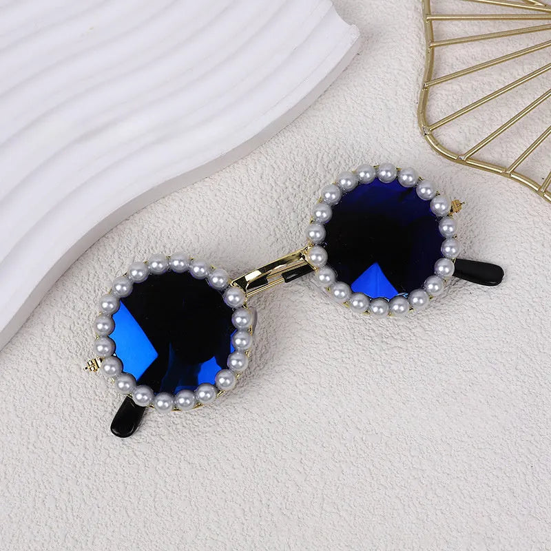 Pearl-rimmed round sunglasses for cats and dogs in multiple colours on a pink background.