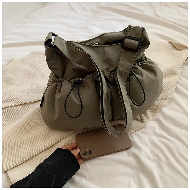 Ultra-light pleated foldable crossbody bag in beige, showing split pocket and crossbody strap.