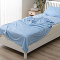 A blue polyester cooling blanket with Q-Max 0.4 technology laid on a bed.