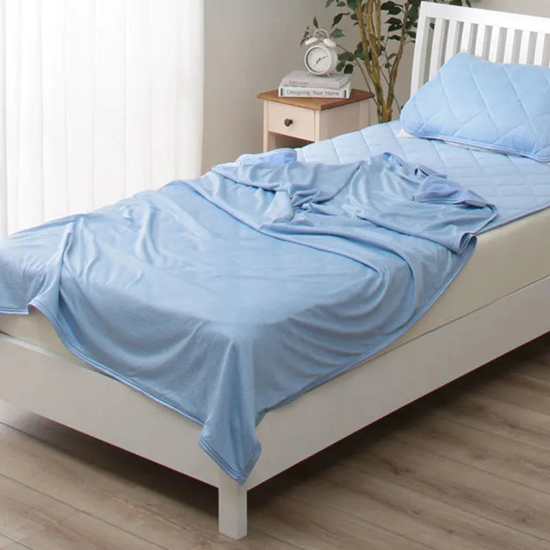 A blue polyester cooling blanket with Q-Max 0.4 technology laid on a bed.