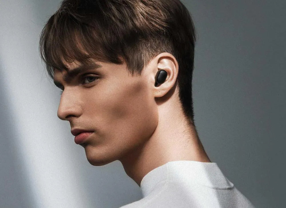 Redmi AirDots black true wireless earbuds next to their white charging case.