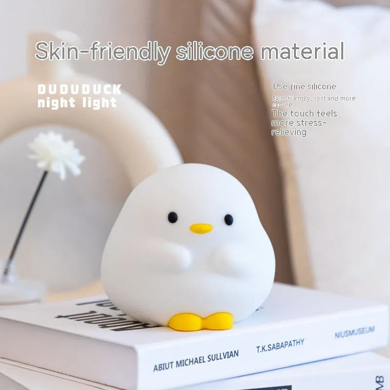 Cute duck-shaped silicone LED night lamp on a bedside table with warm light