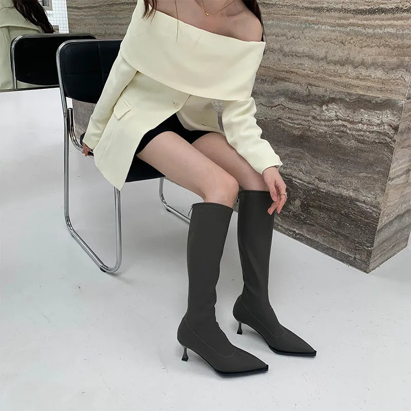 Black women's knee-high pointed toe boots with a stiletto heel and back zip fastening.