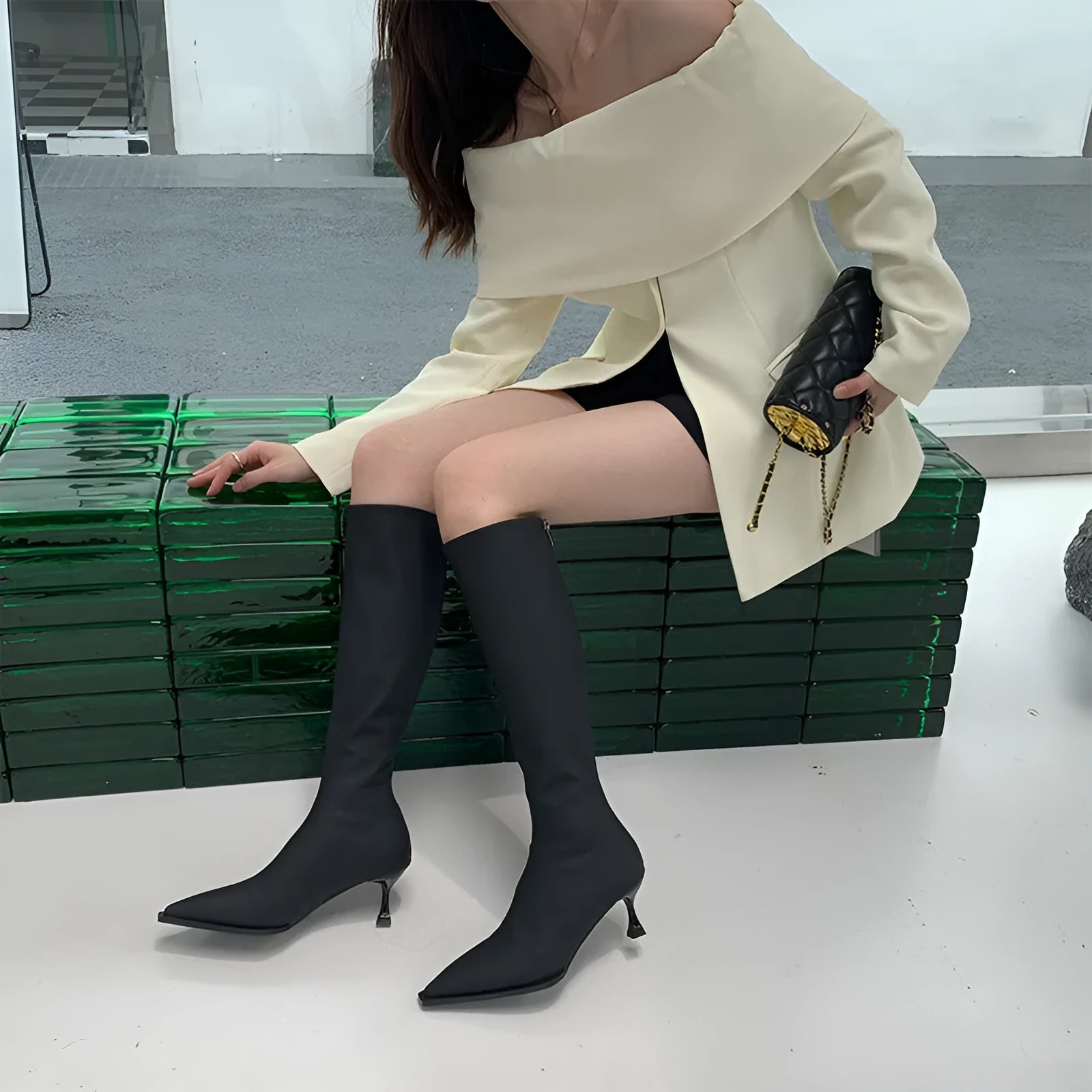 Black women's knee-high pointed toe boots with a stiletto heel and back zip fastening.