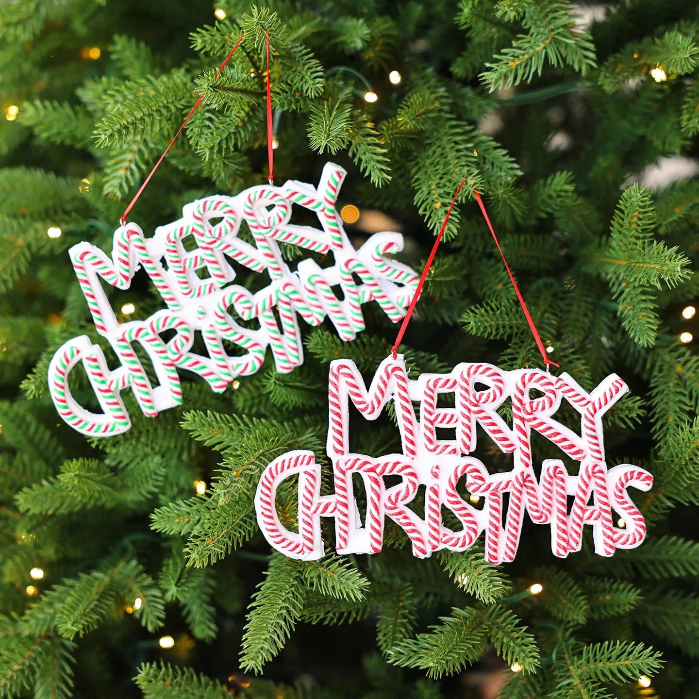 Merry Christmas letter plate polymer clay tree ornament in red, white and green plastic hanging on a tree branch