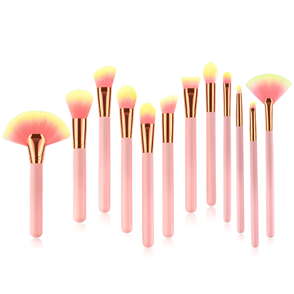 Twelve pink makeup brushes with nylon bristles and wood handles laid out in a row on a light background