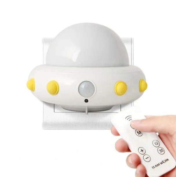 Blue UFO-shaped bedside night light with remote control on a wooden table.