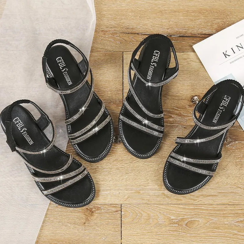 Women's silver flat sandals with rhinestone decoration and an elastic band, showing the round toe and rubber sole.