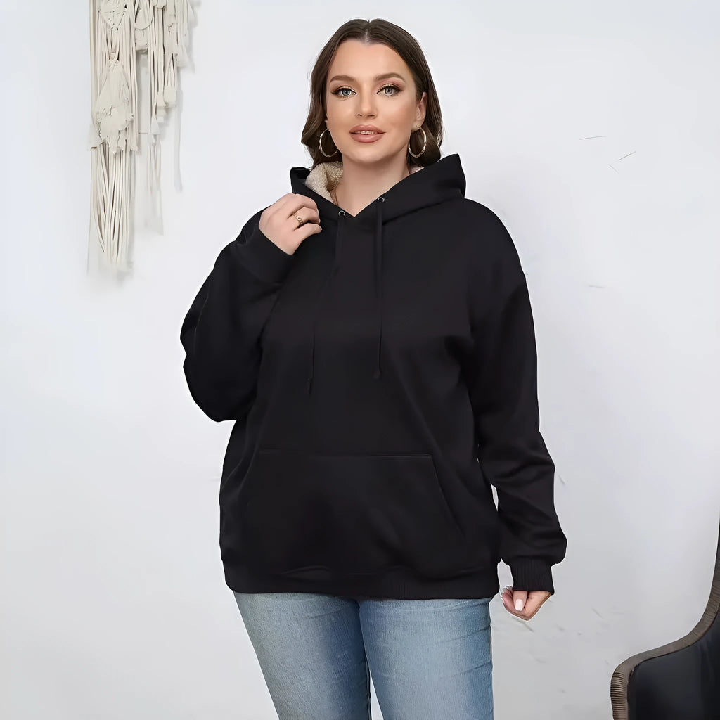 A woman wearing a thick, grey, loose-fit hooded sweatshirt with a 3D pattern and front pockets.