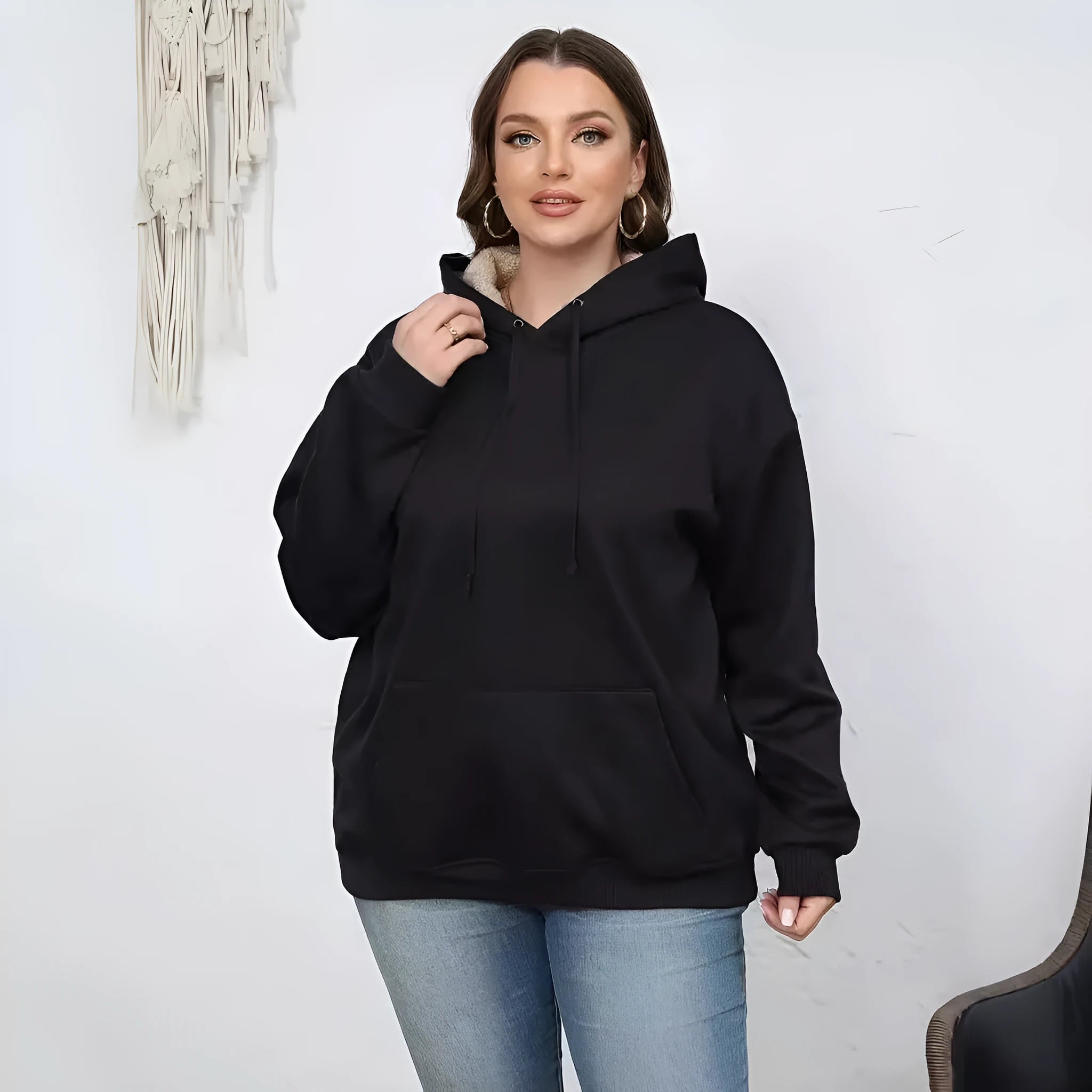 A woman wearing a thick, grey, loose-fit hooded sweatshirt with a 3D pattern and front pockets.