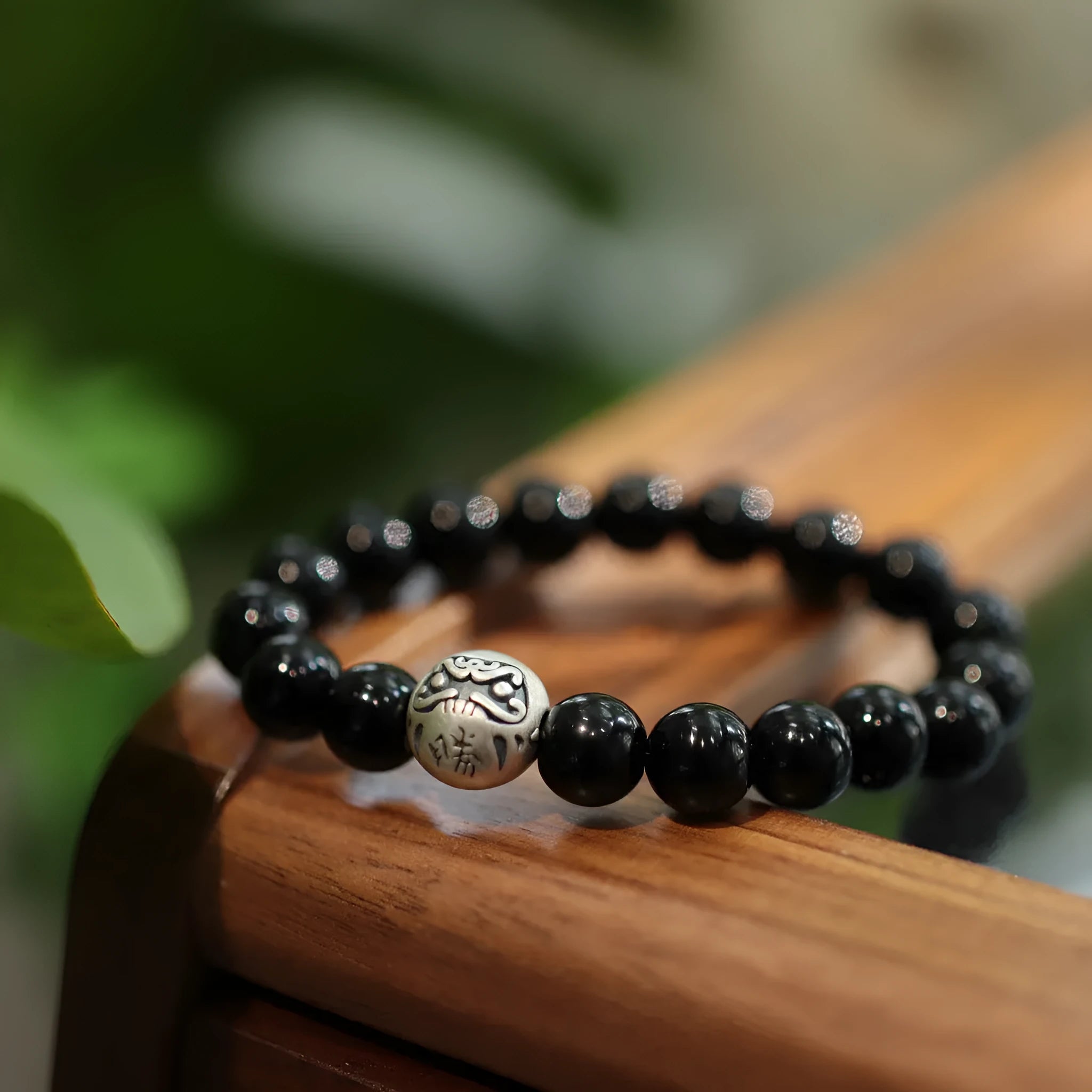 Black agate bracelet with 10mm beads and a sterling silver clasp on a wrist.