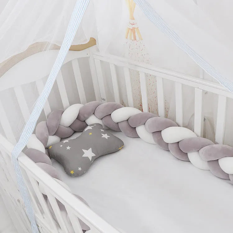 Braided knot crib bumper in spandex velvet, shown bending to fit a white wooden cot.