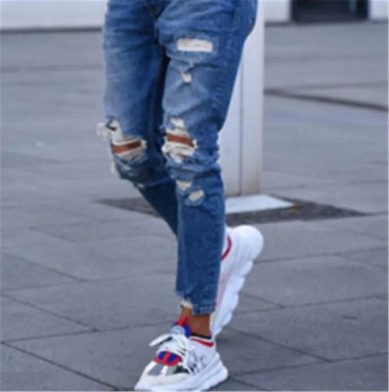 Men's blue jeans with hole detailing showing cotton fabric texture and distressed design