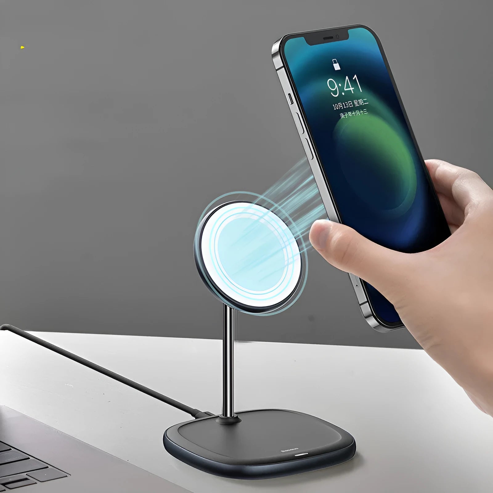 Black magnetic wireless charging stand holding an iPhone 12 Pro on a desk.