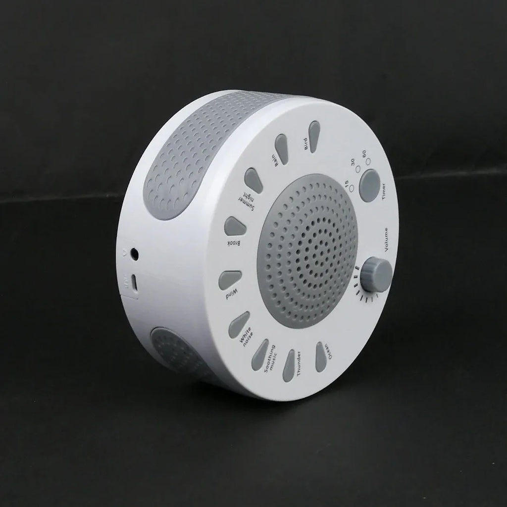 White portable white noise sleep sound machine with control knob on a bedside table.