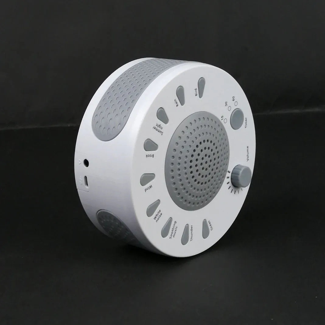 White portable white noise sleep sound machine with control knob on a bedside table.