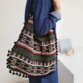 Green geometric tribal tasselled tote bag with oval shape, open top, and two handles, shown on a flat surface