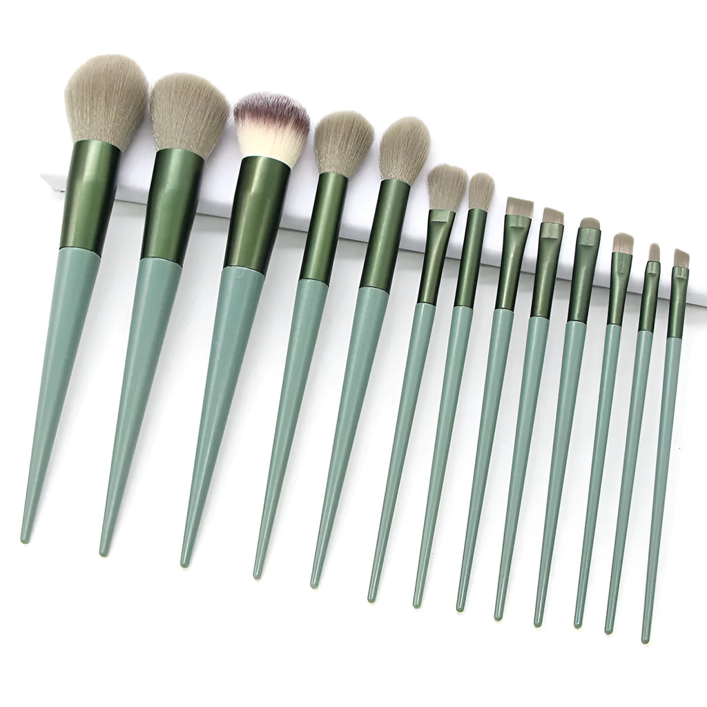 13 green makeup brushes with fibre wool bristles and aluminium tubes arranged on a surface