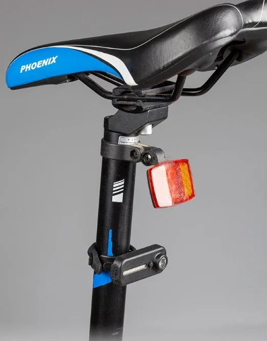 Black bicycle warning taillight with clip and strap on a backpack strap, showing red and blue flash mode