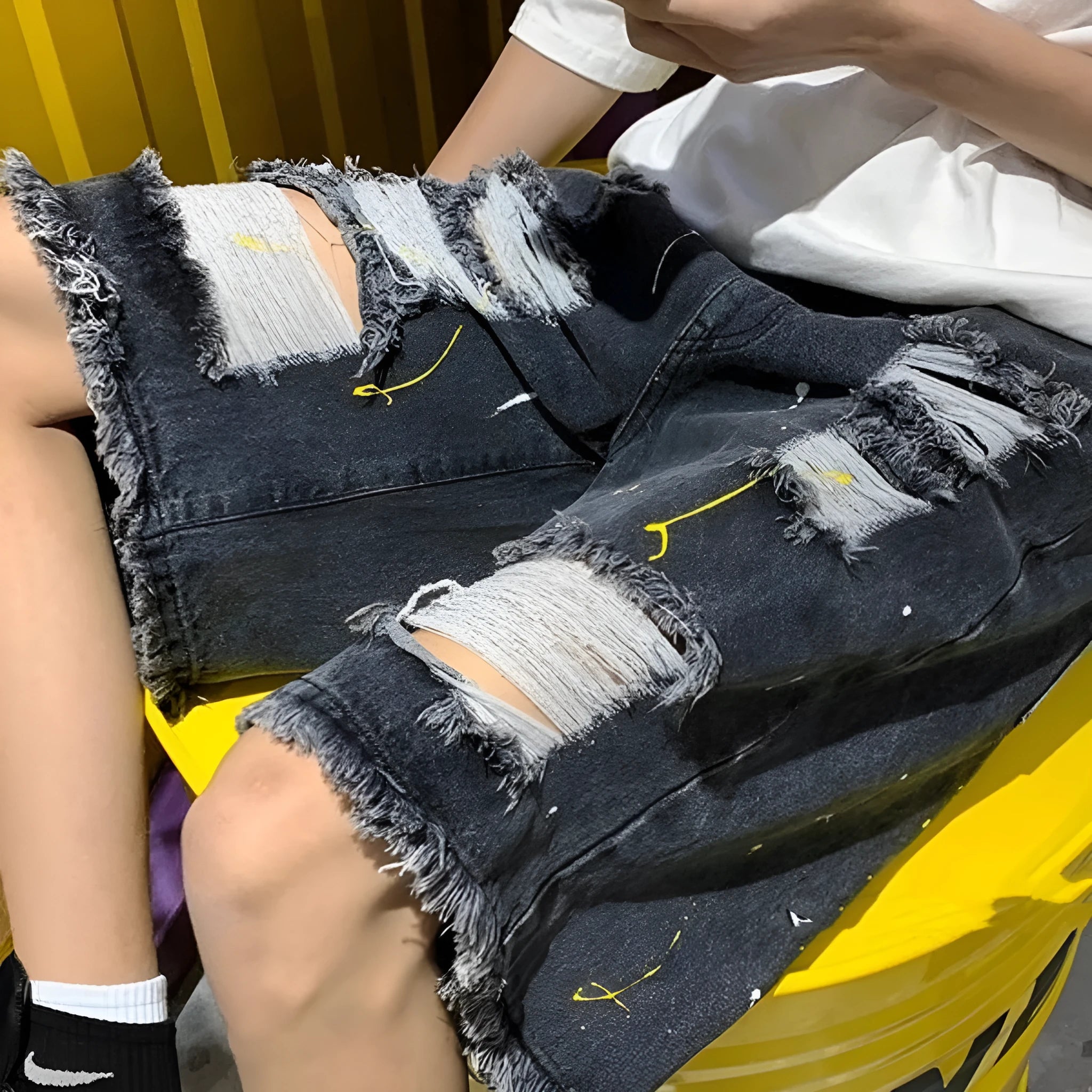 Man wearing loose-fit light blue denim shorts with water-washed distressed fabric and a fifth pants length.