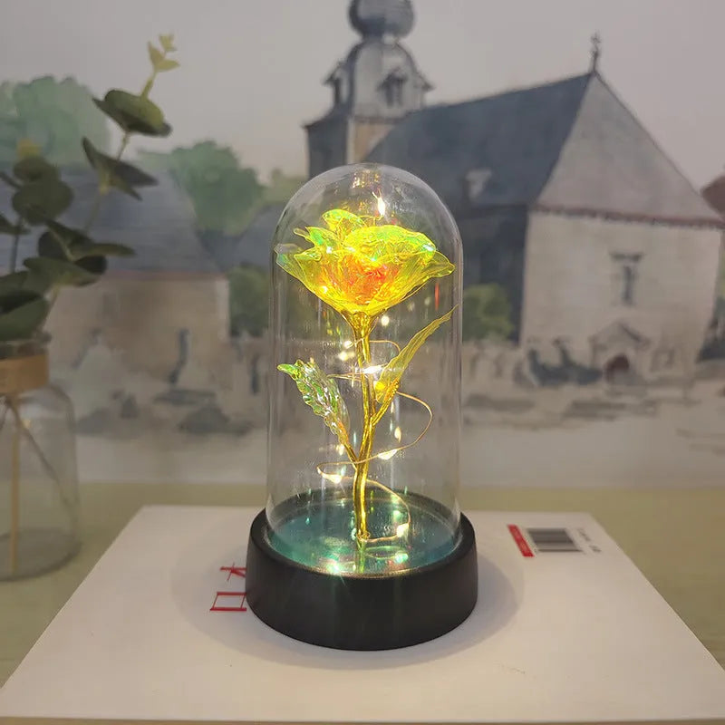 Small decorative night lamp with glass cover, plastic flower, and black base on a pink box.