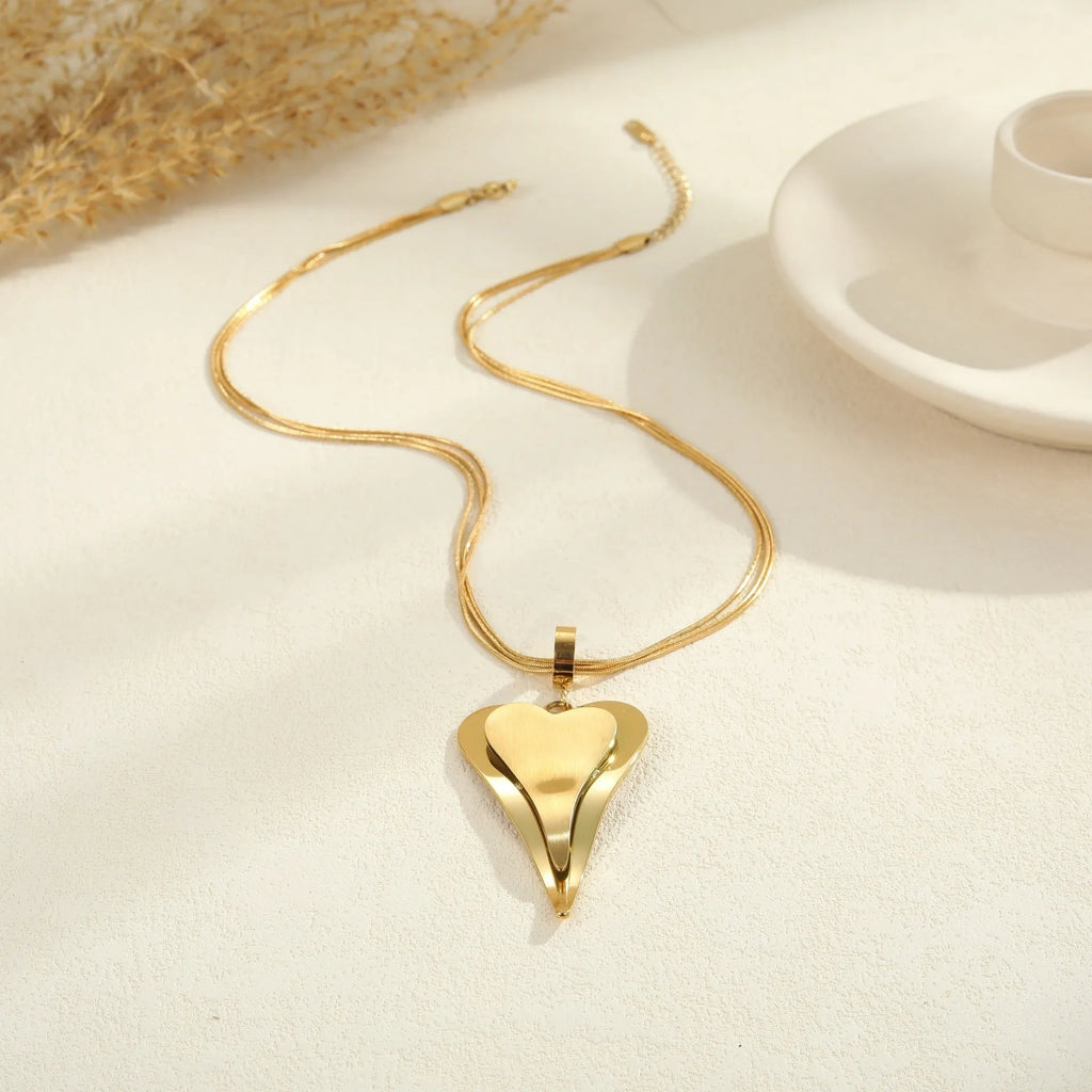 Close-up of a women's stainless steel necklace with a double heart snake bones chain and a geometric pendant.