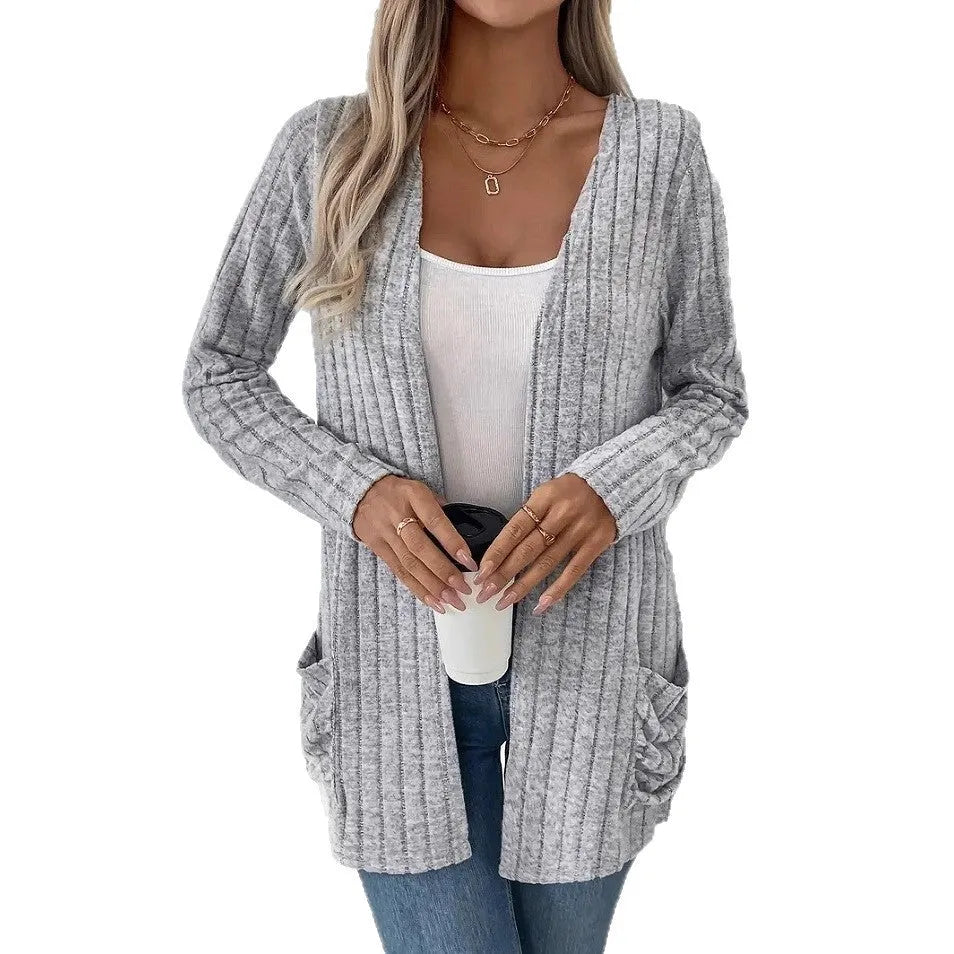 Plus size woman wearing a long sleeve grey cardigan with front pockets, loose fit.