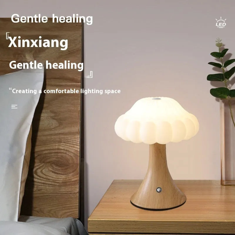 Small mushroom-shaped touch night lamp in wood grain finish on a wooden table.