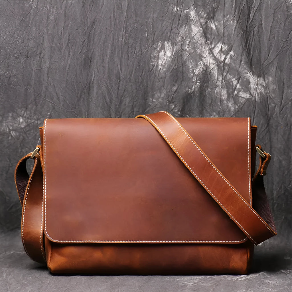 Men's vintage brown leather messenger bag with adjustable strap, shown open to reveal internal organiser pockets.