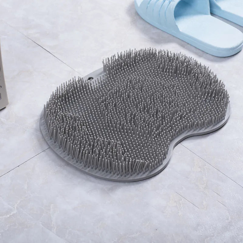 Orange TPR bath brush with silicone bristles and suction cups on base, shown on bathroom tiles.
