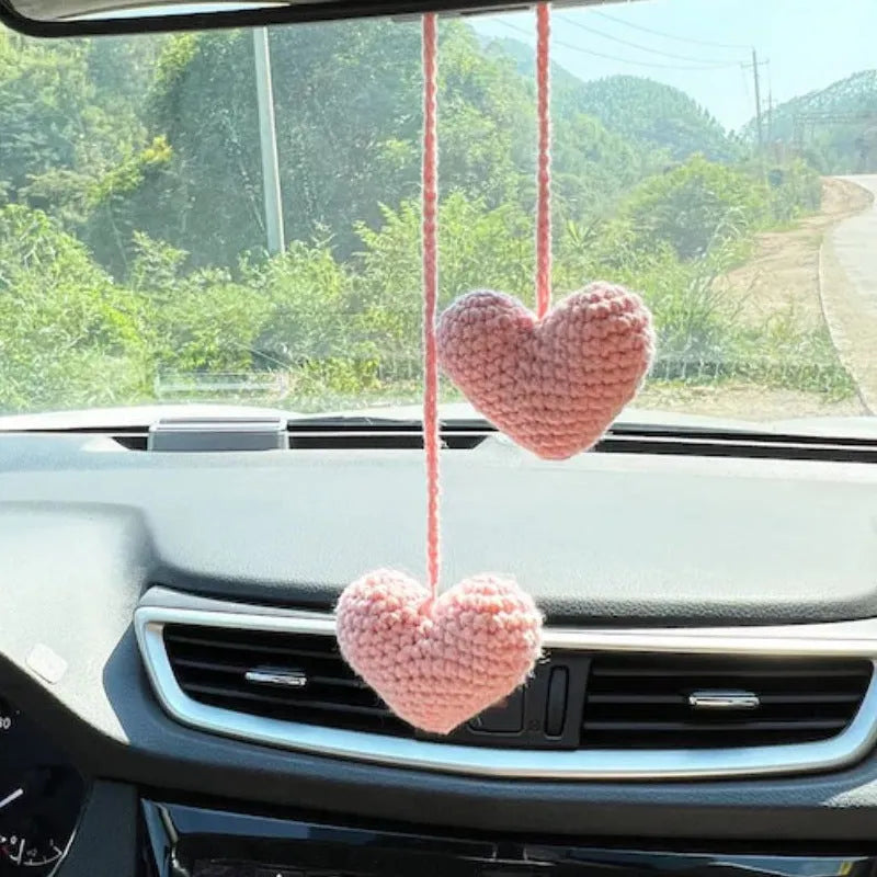 Green and white knitted wool car plant decoration with macramé texture and a white hanging rope.