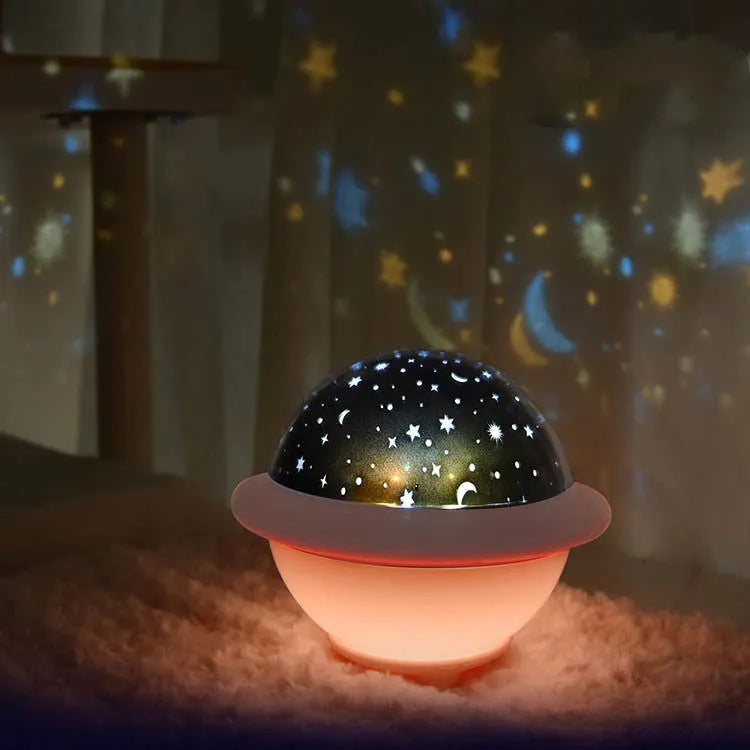 Pink UFO-shaped LED night light projecting a starry sky pattern on a wall.