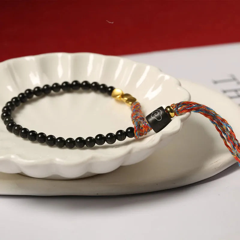 Hand-woven obsidian carrying strap bracelet showing textured weave detail and narrow 4mm width