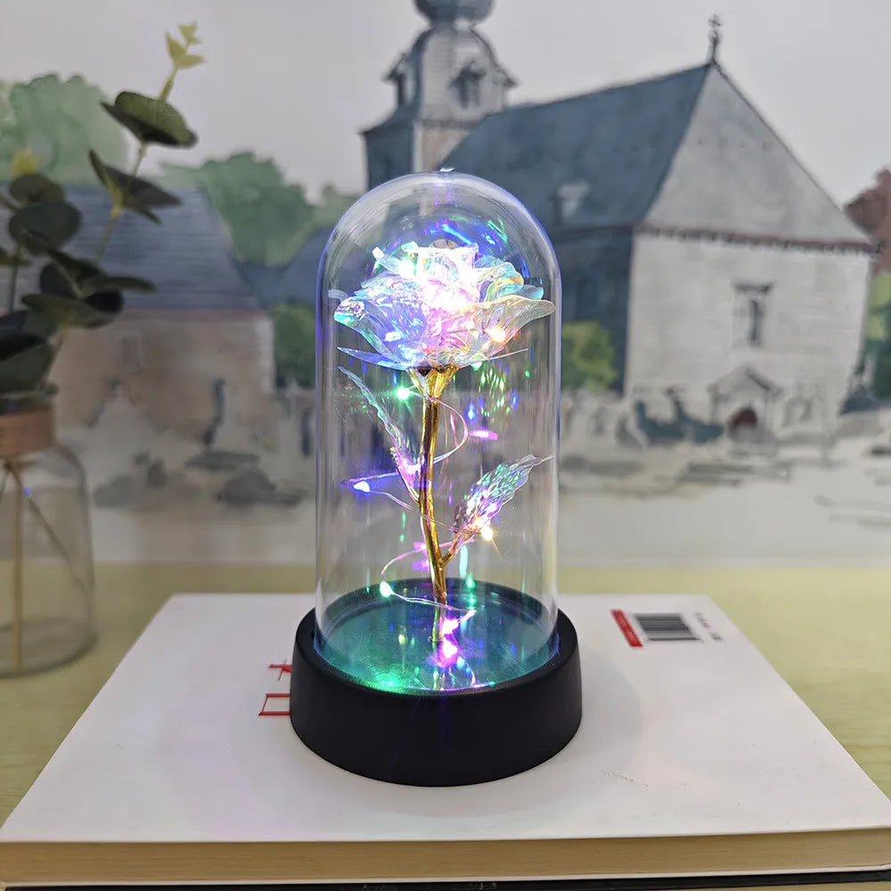 Small decorative night lamp with glass cover, plastic flower, and black base on a pink box.