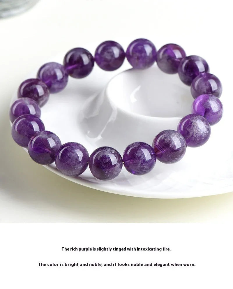 Natural feather amethyst crystal bracelet with scattered purple beads on a white background.