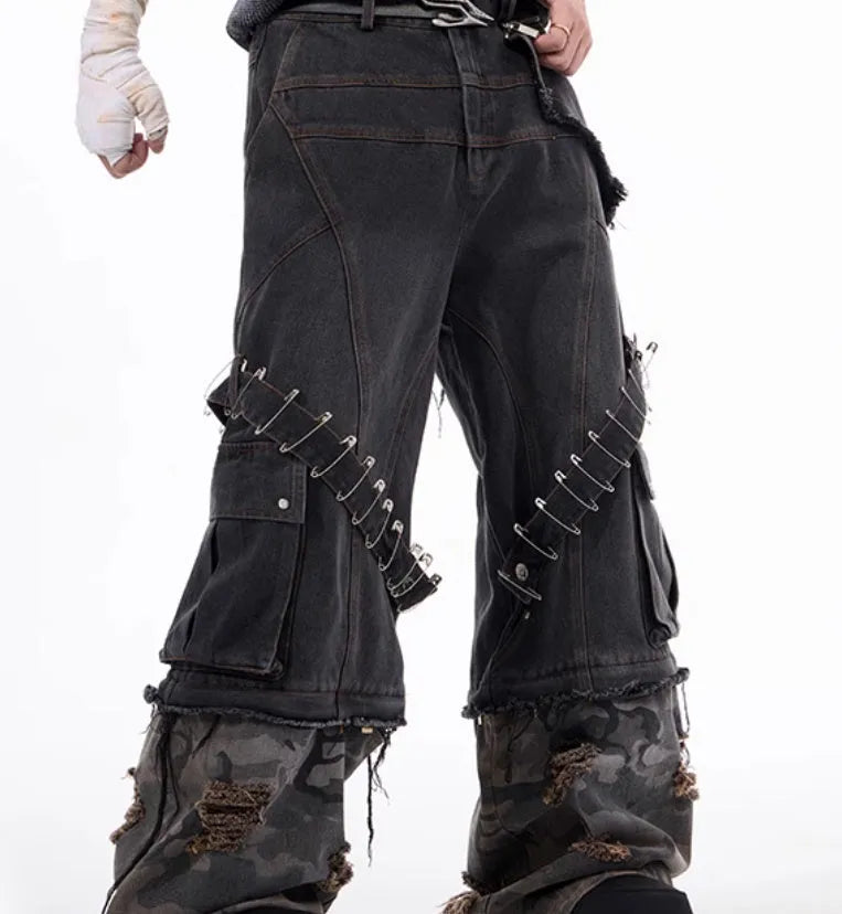 Grey men's jeans with camouflage pattern and spliced construction, showing pin and ribbon details.