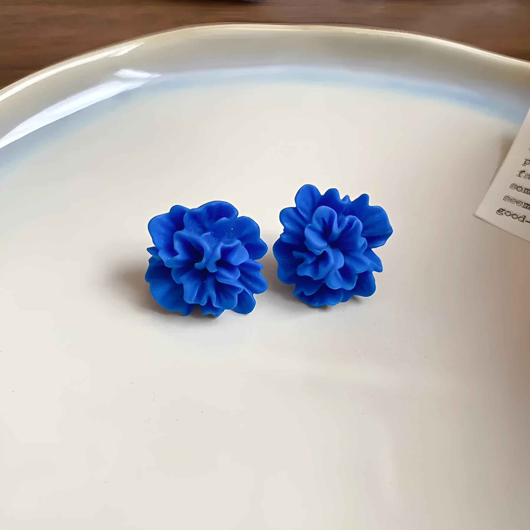 Geometric cloth earrings with blue resin flower detail and round design elements