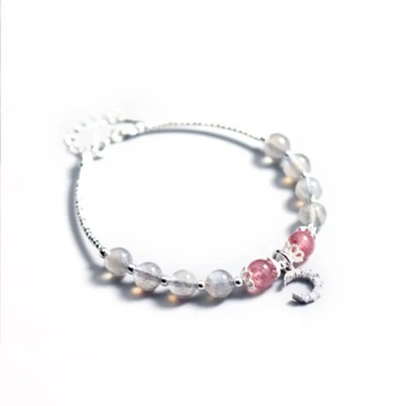 Adjustable natural moonstone bracelet with crescent moon charm on a wrist, showing extension chain.