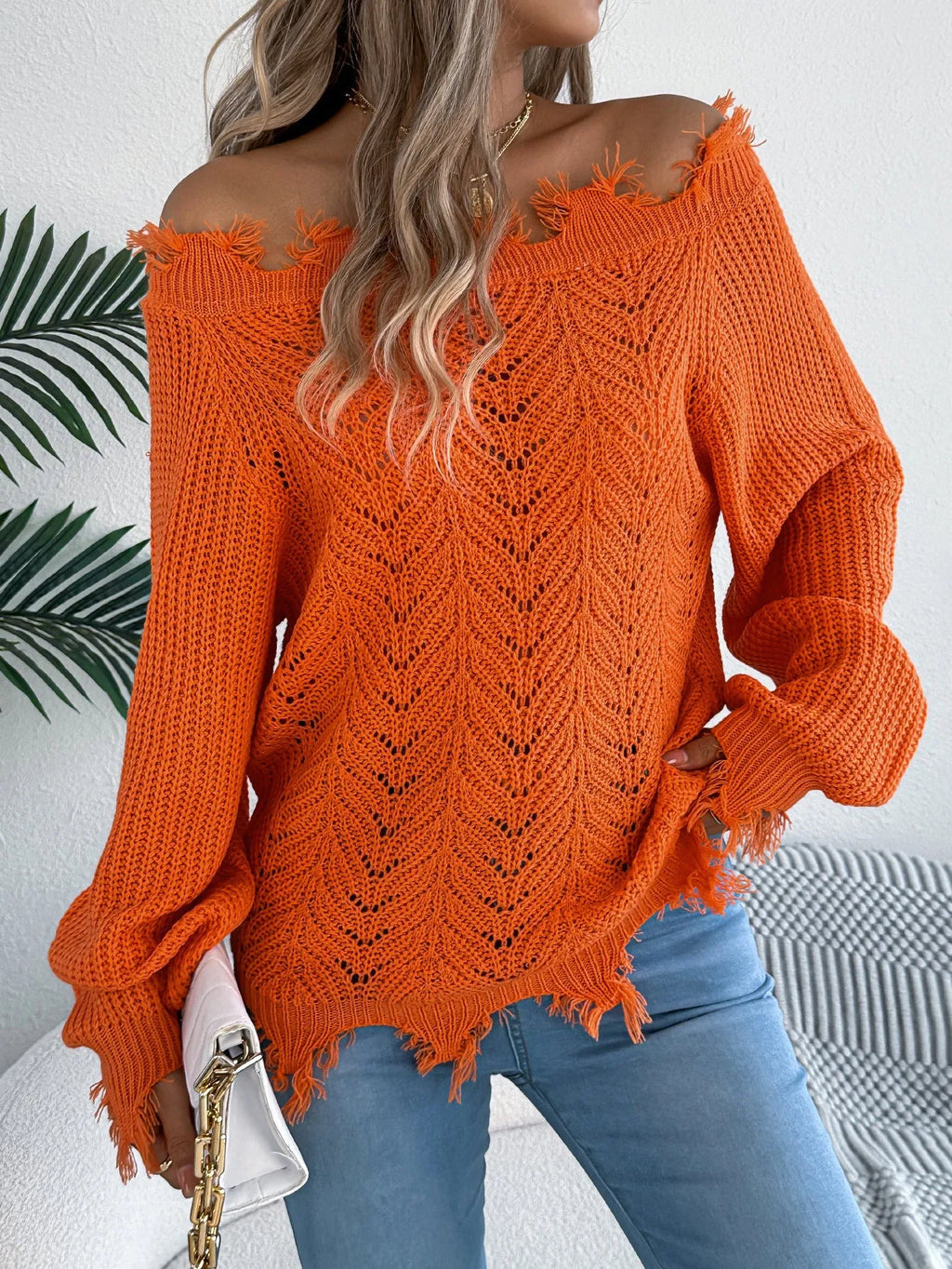 White hollow-out off-the-shoulder long sleeve pullover sweater laid flat.
